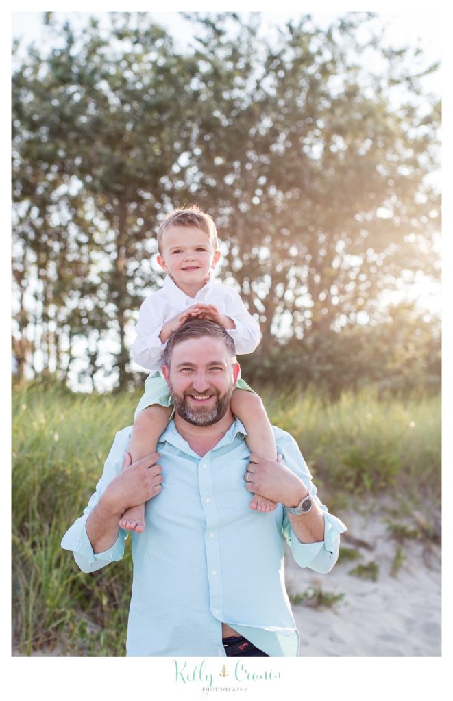 A man holds his son on his shoulders during their Cape Cod Family Photos. 