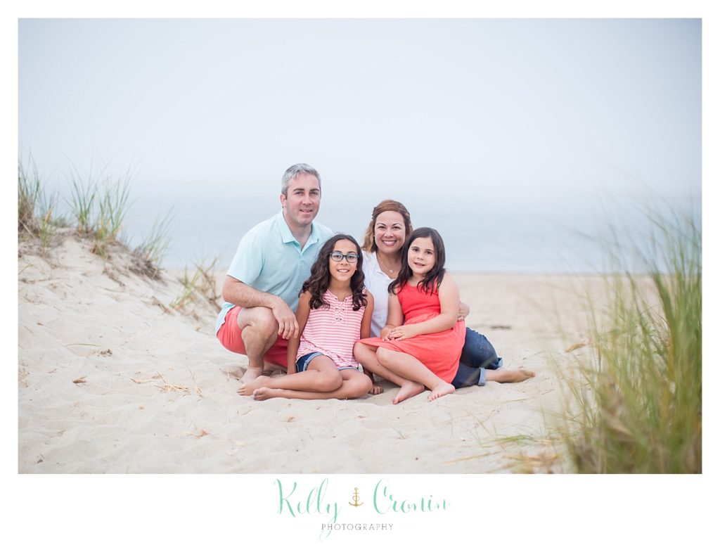 A family sits in the sand during their Family Session. 
