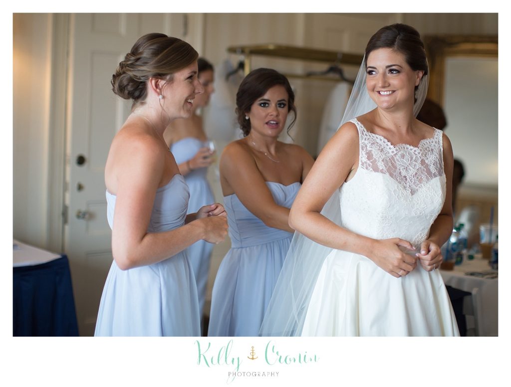 Bridesmaids help a bride get into her dress. 