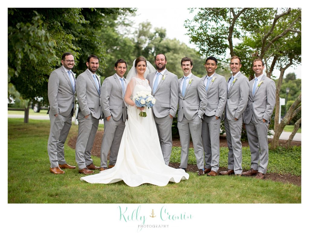 A bride stands with the groomsmen. 