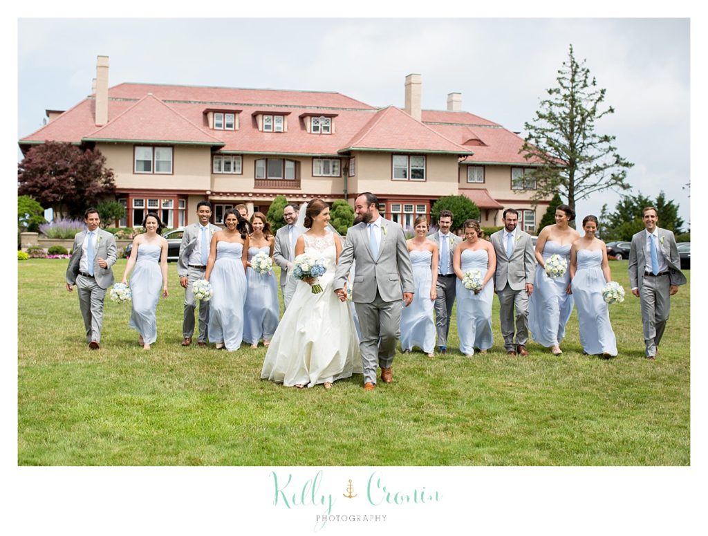 A bride and groom stand in front of their wedding party. 