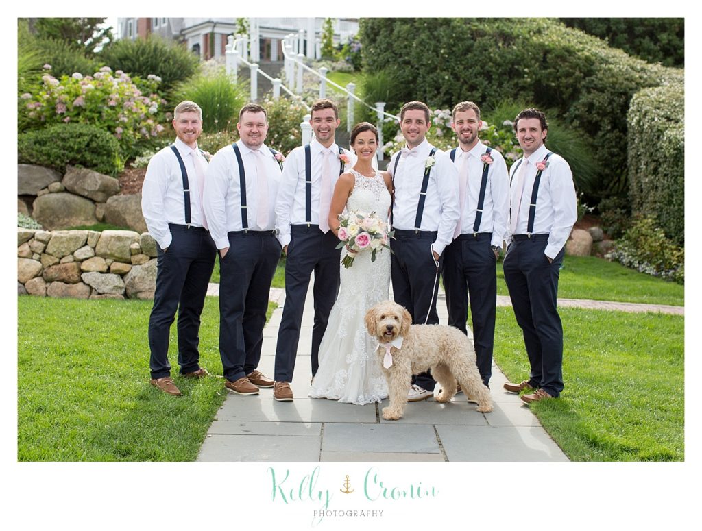 Groomsmen pose for a photo with a puppy. 