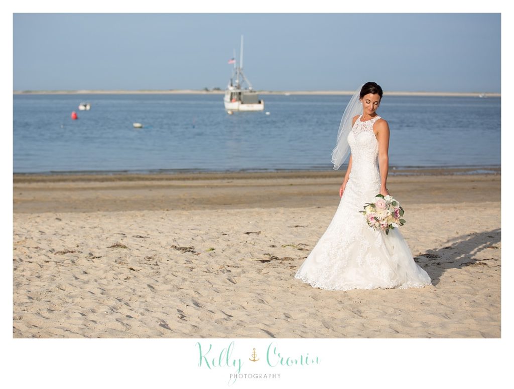A bride stands in front of the shoreline. 