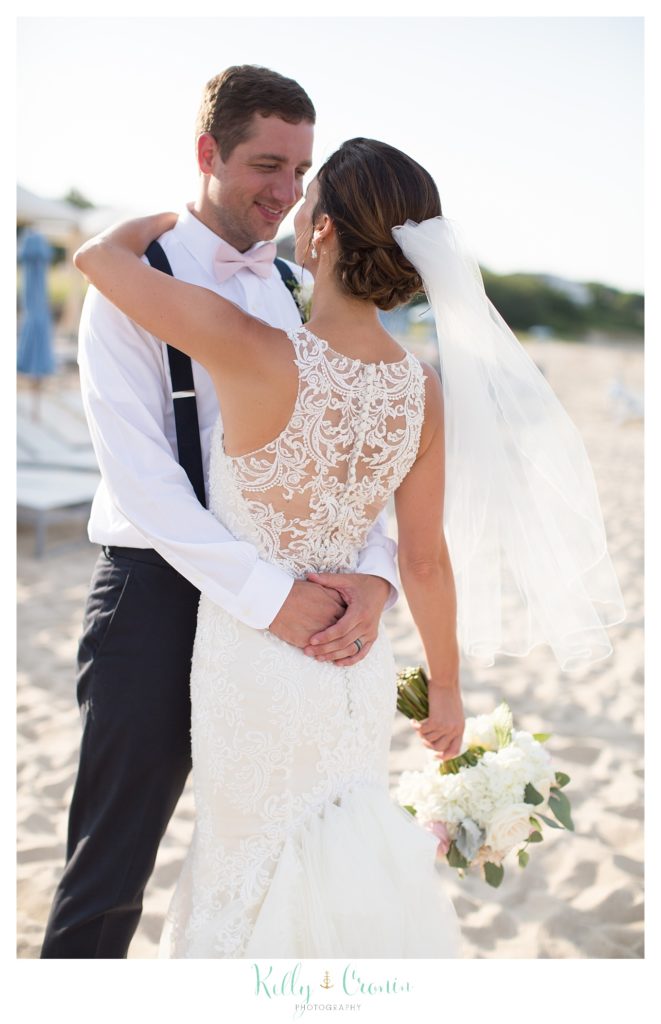 A groom wraps his arm around his bride for a hug. 