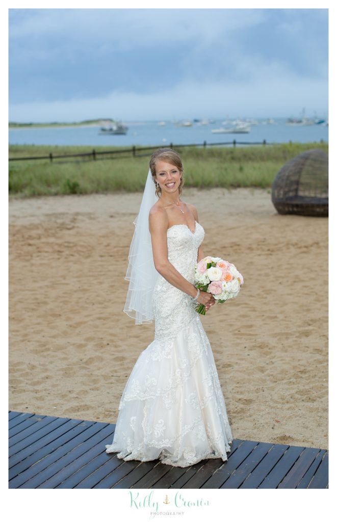 A bride stands in the sand on the shore 