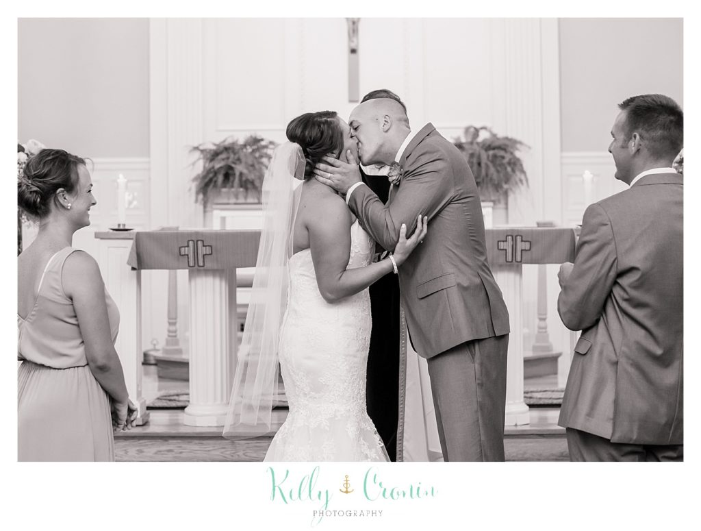 A groom and bride share their first kiss. 