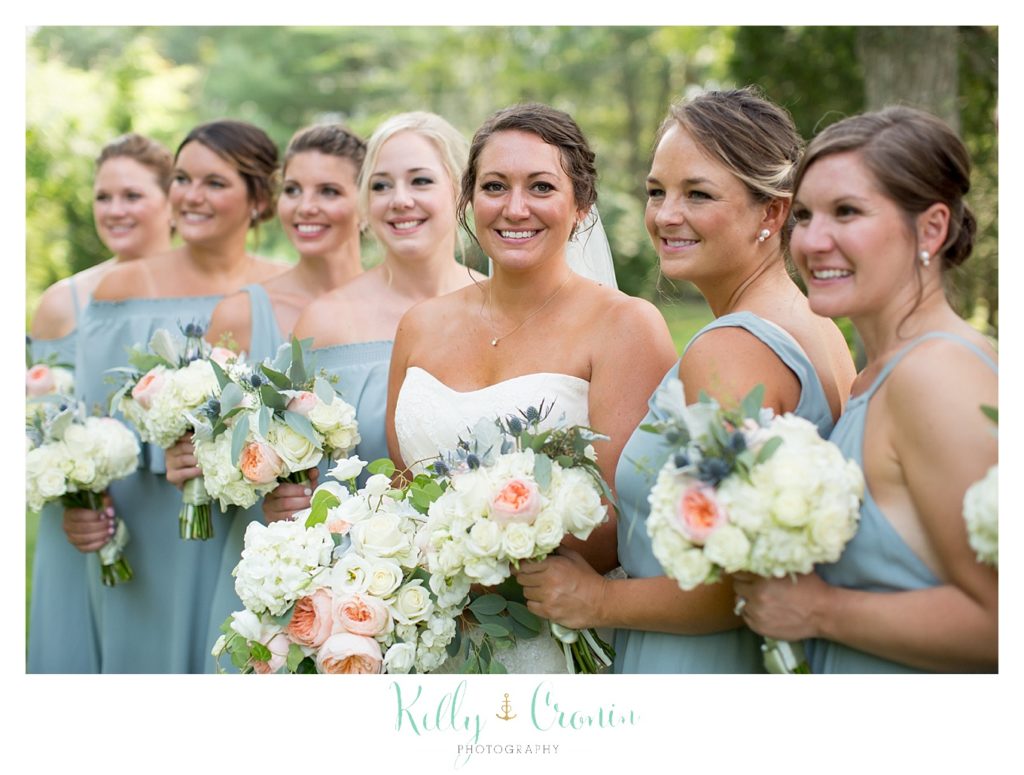A bride stands in front of her bridal party. 