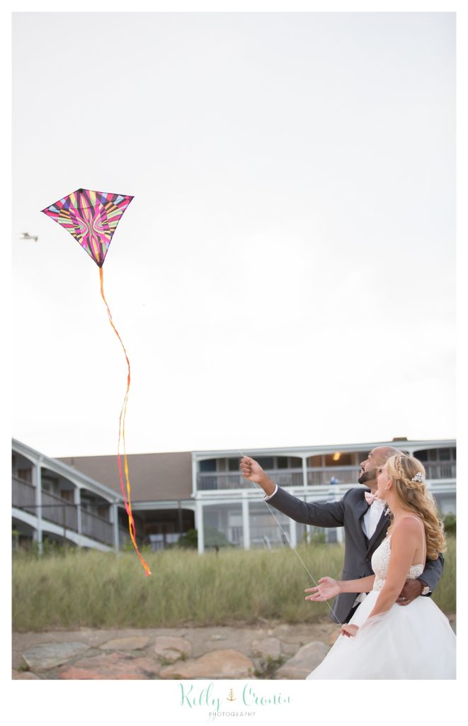 A bride and groom fly a kite. 