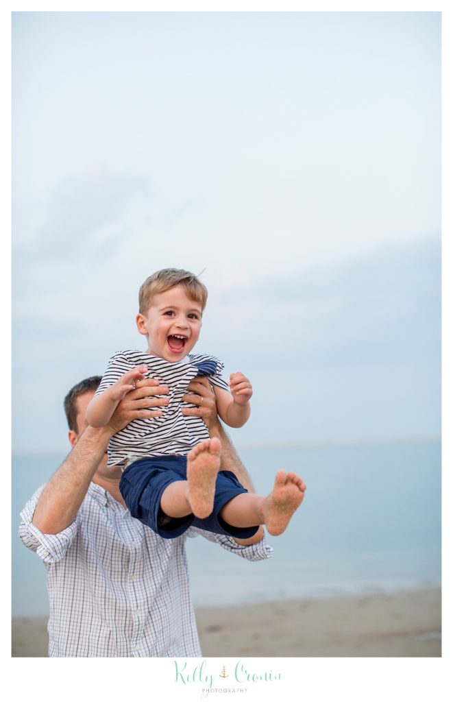 A dad throws his boy up into the air. 
