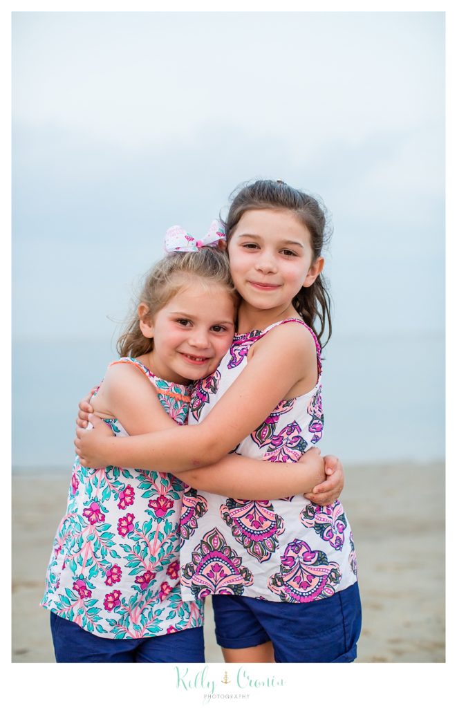 Two sisters hug each other around the waist for their family pictures. 
