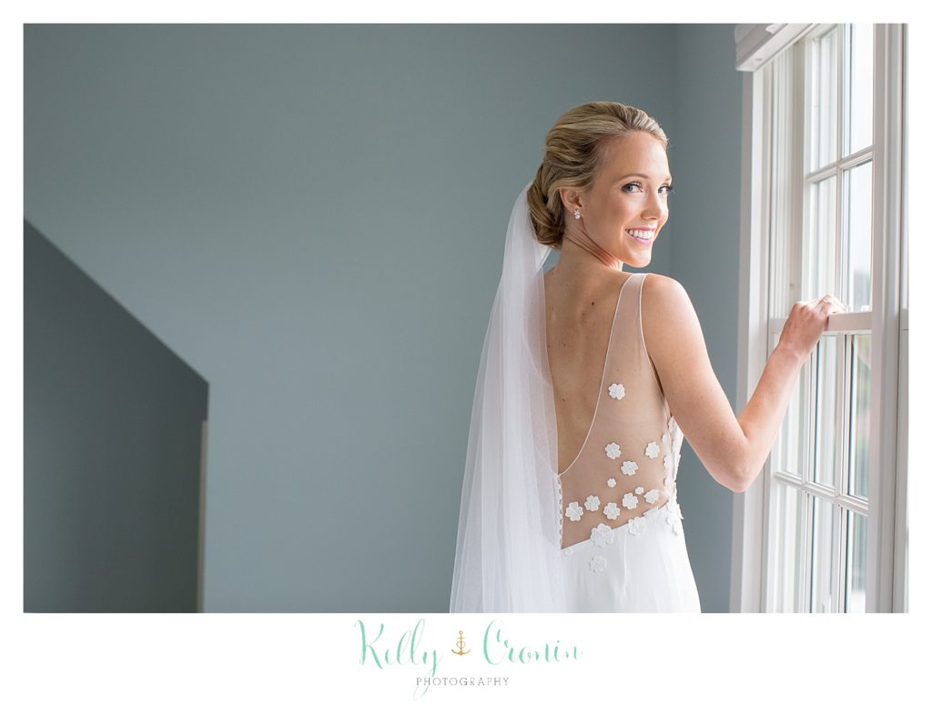 A bride poses by a window for a photo.