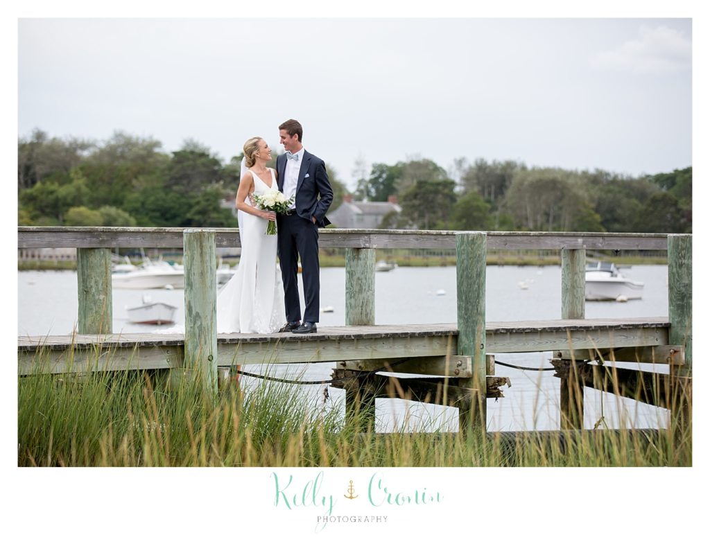 A bride and groom stand on a pier together.