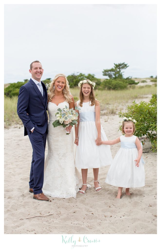 A bride and groom stand with their flower girls. 