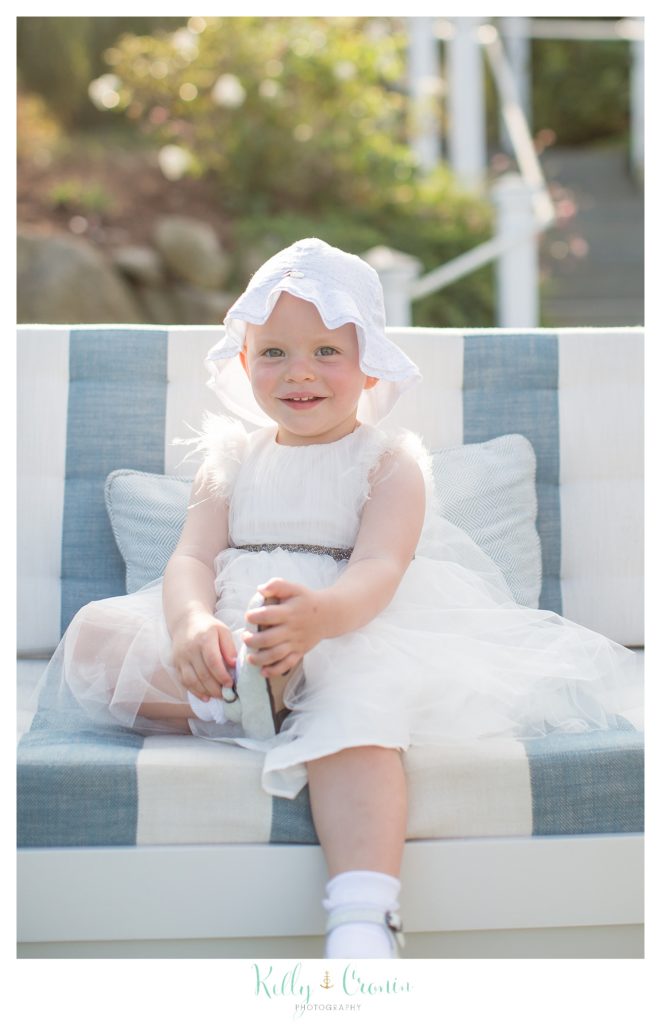 A small girl sits on the beach in wedding clothes. 