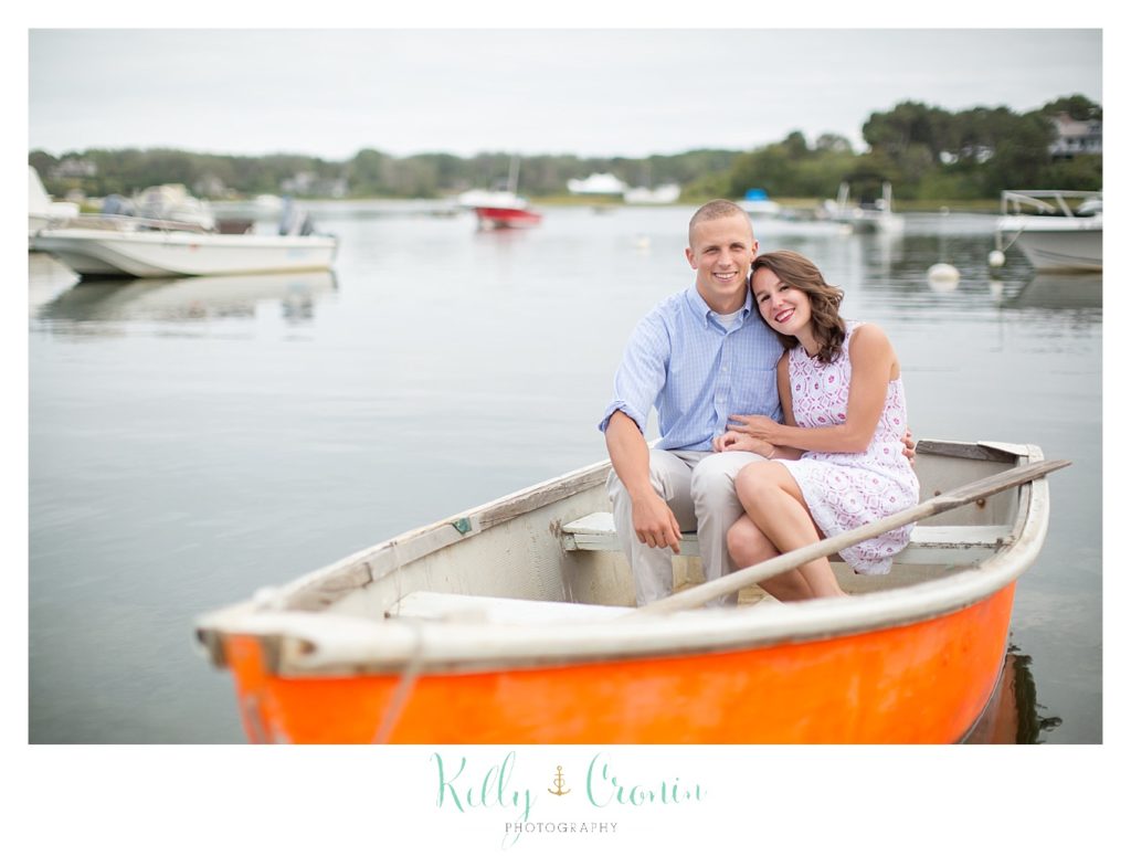 An engaged couple sit in an orange boat together