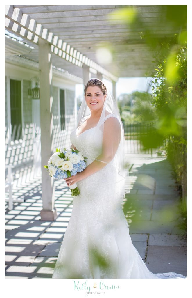 A bride holds her bouquet on a porch. 