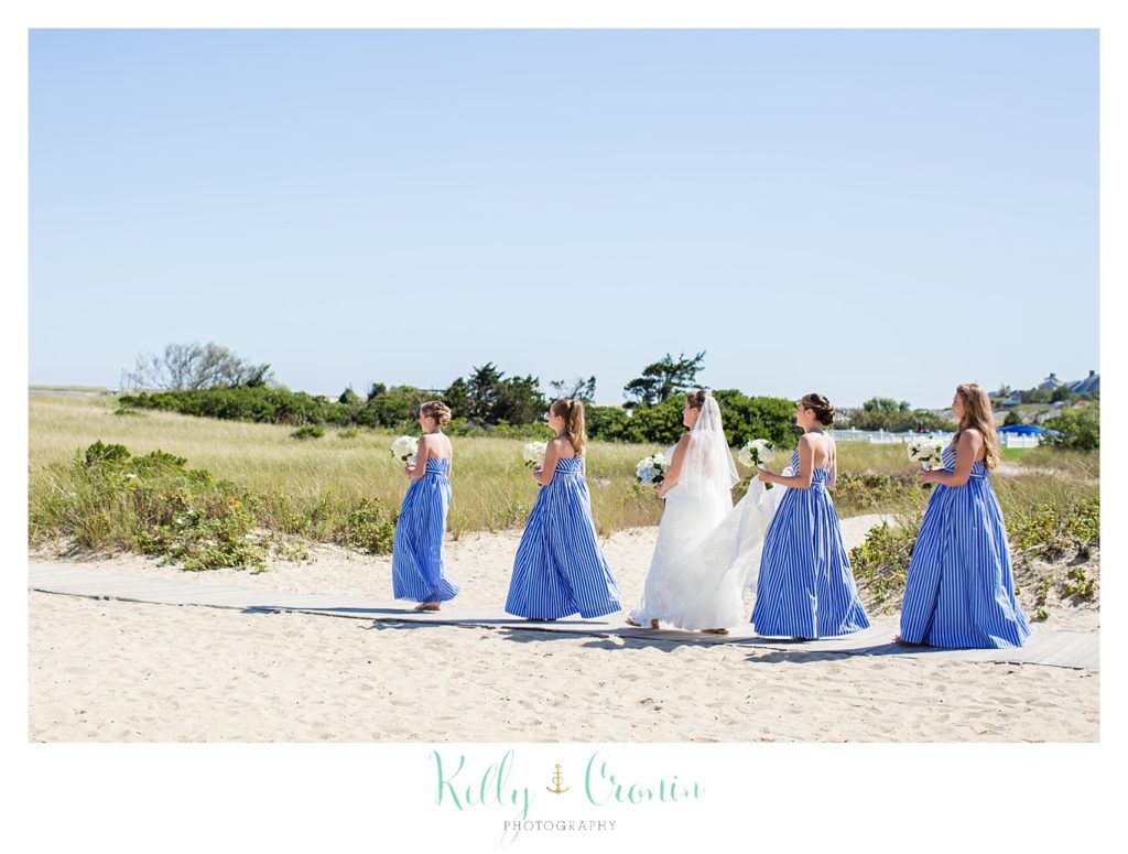 A bride walks on the beach with her bridesmaids. 