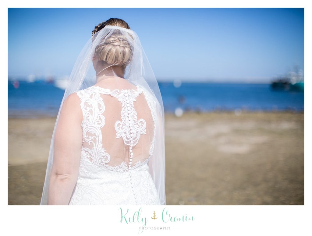 A bride looks out into the ocean. 