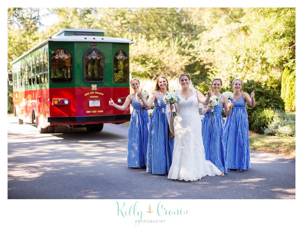 A bridal party stands in front of a trolly. 