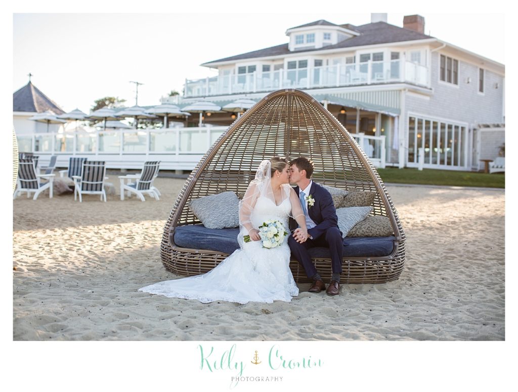 A bride and groom sit in a bungalow on the beach. 