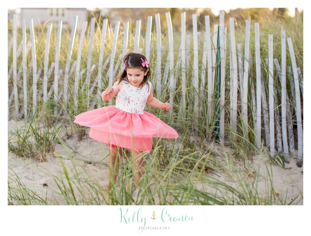 A little girl twirls in her pink dress. 