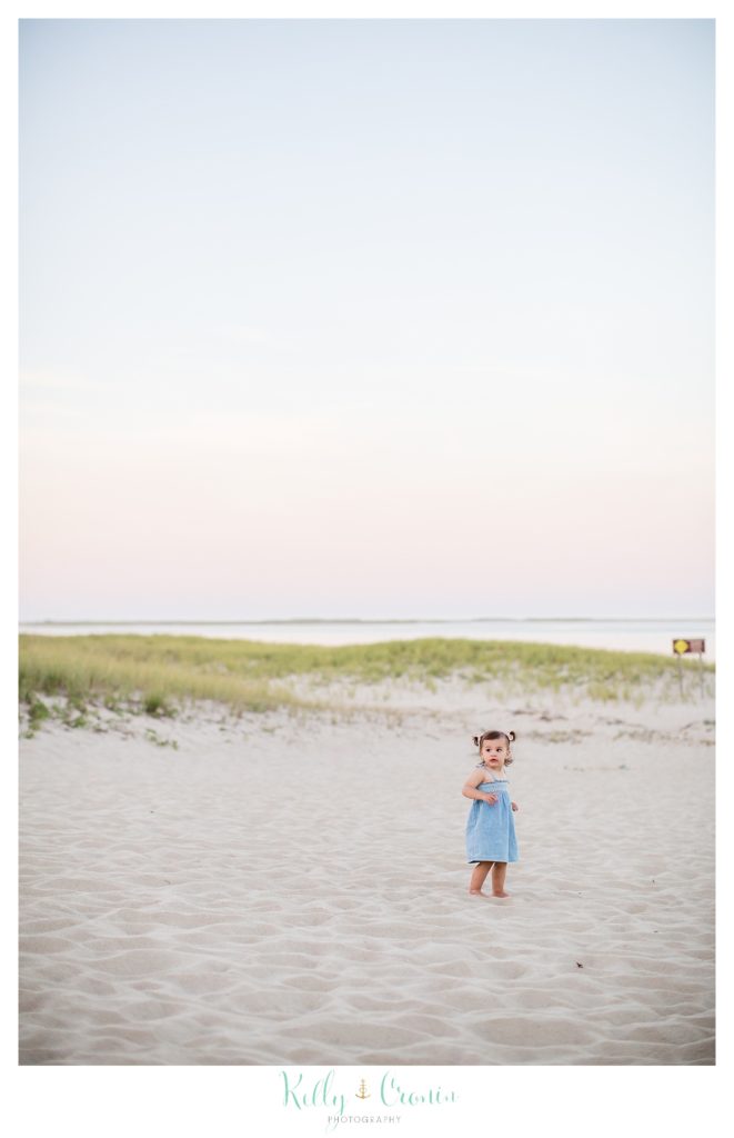 A little girl walks out onto the beach. 