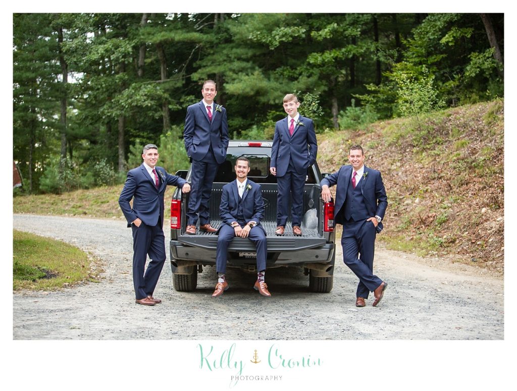 A groom stands on a truck with his groomsmen 