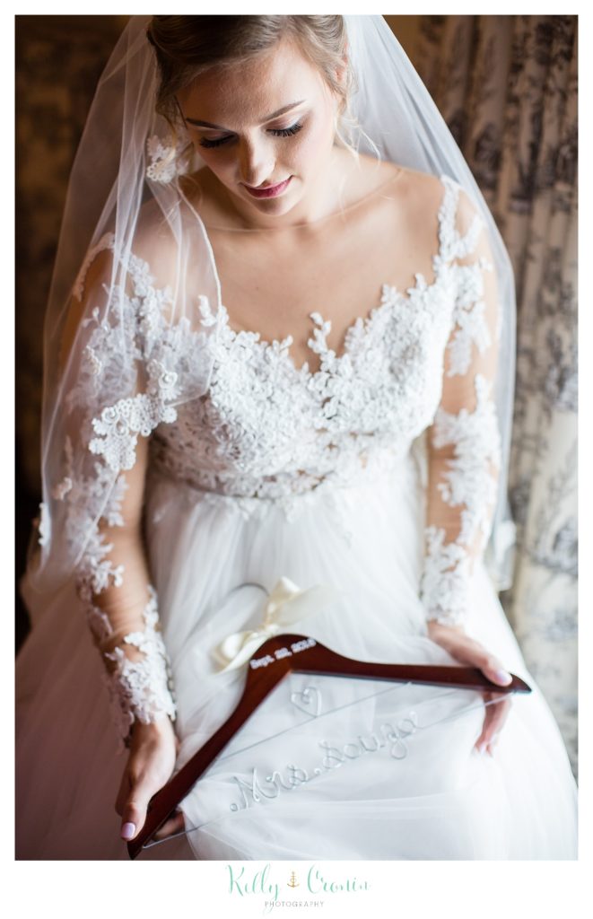 A bride holds a wooden hanger. 